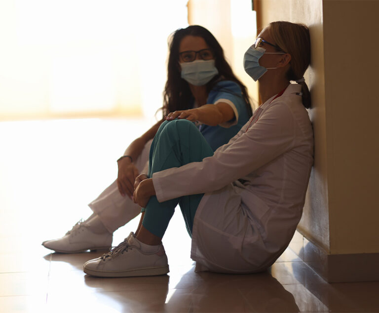 Photo of healthcare workers in masks looking burned out