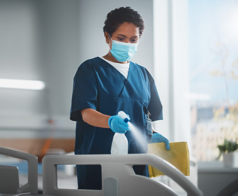 Healthcare worker cleaning hospital bed