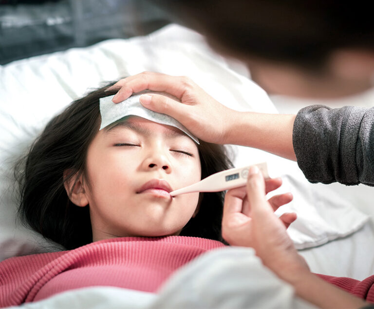 Child with fever being tended to by caretaker