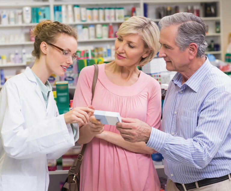 Couple reviewing drug package with a pharmacist