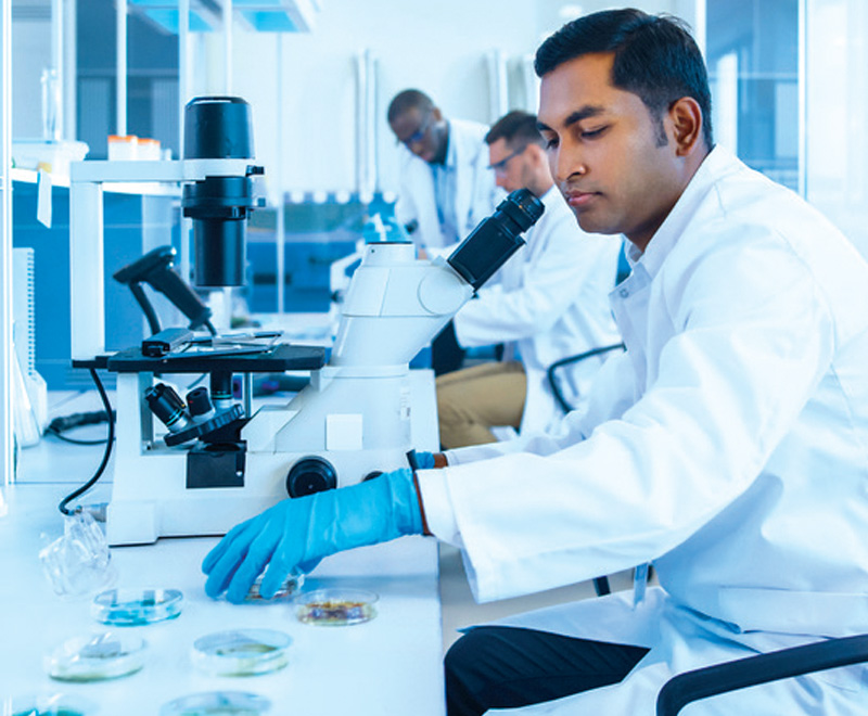 Photo showing researcher looking in microscope in lab