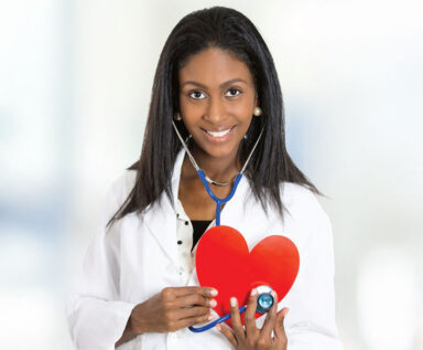 Photo of a female doctor holding a red heart-shaped cut out and a stethoscope